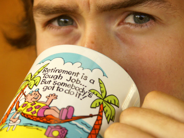 Close-up on my face as I drink from a mug that that says Retirement is a tough job... But somebody's got to do it!